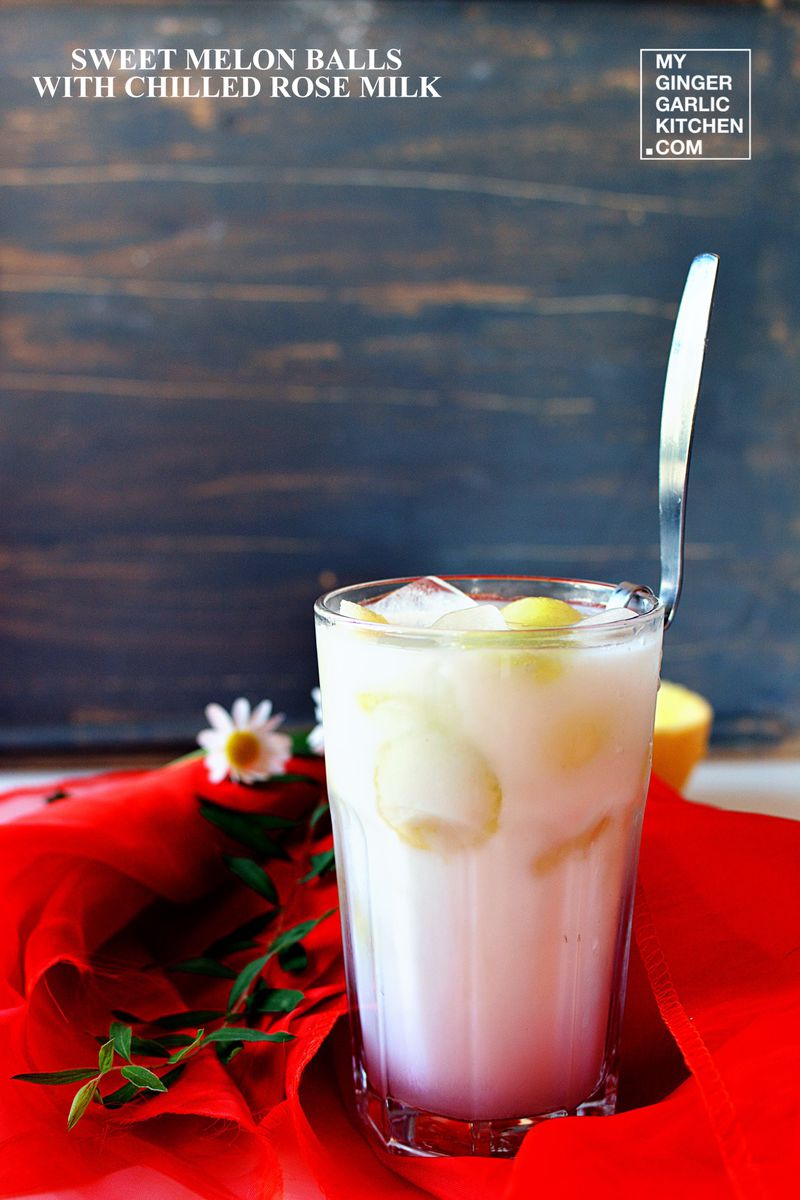 a glass of chilled rose milk with sweet melon balls some ice and some flowers