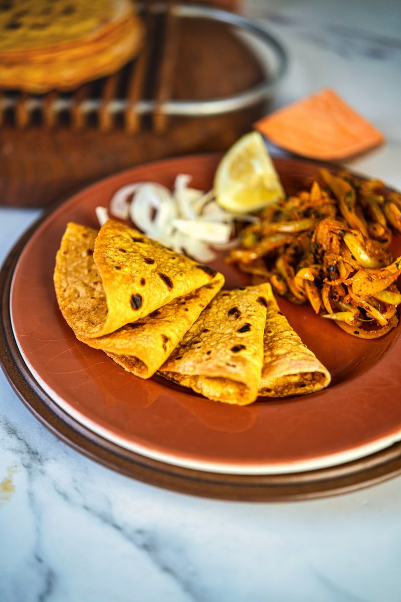 Folded sweet potato flatbread served with grilled vegetables, onions, and lemon on a brown plate, ready for a delicious meal.