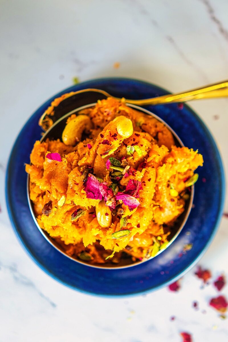 Top view of creamy sweet potato halwa dessert with mixed nuts and rose petals, perfect Indian festival sweet dish