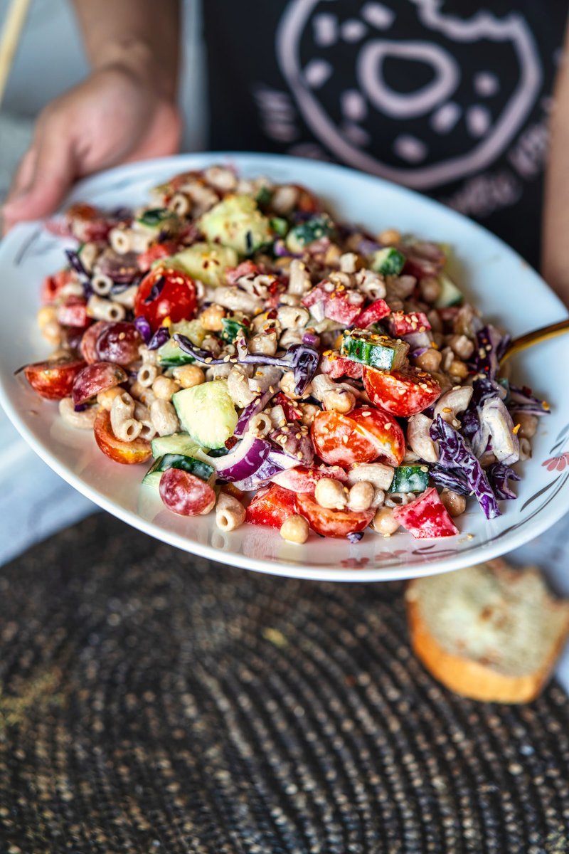 A colorful Tahini Pasta Salad with fresh vegetables served on a white plate.