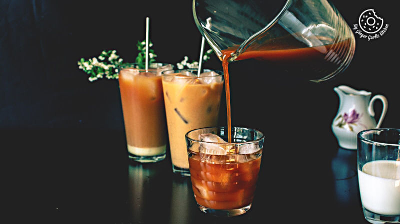 a pitcher pouring thai iced tea into a glass of iced coffee