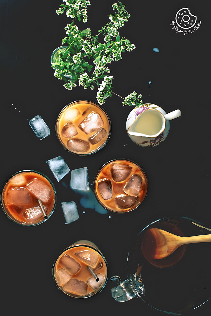 four glasses of thai iced tea drink with ice cubes and a wooden spoon