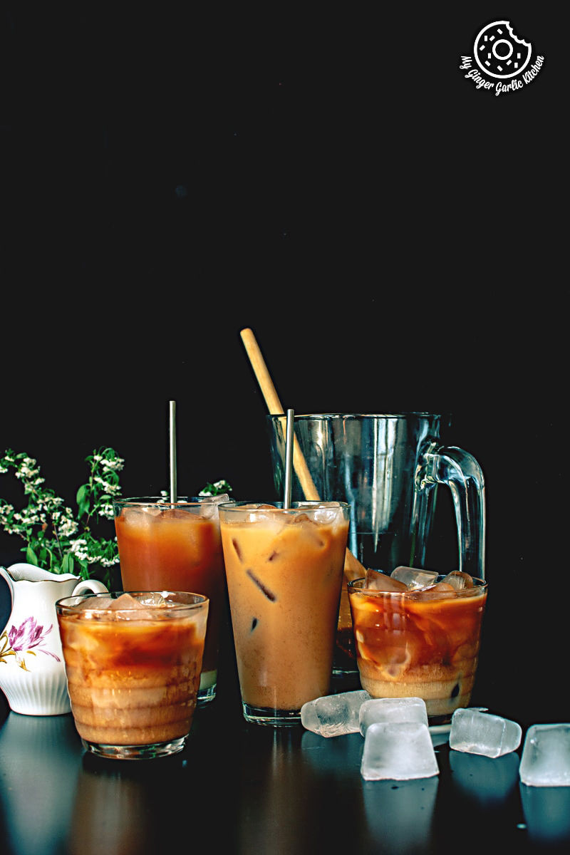 four glasses of thai iced tea on a table with ice cubes