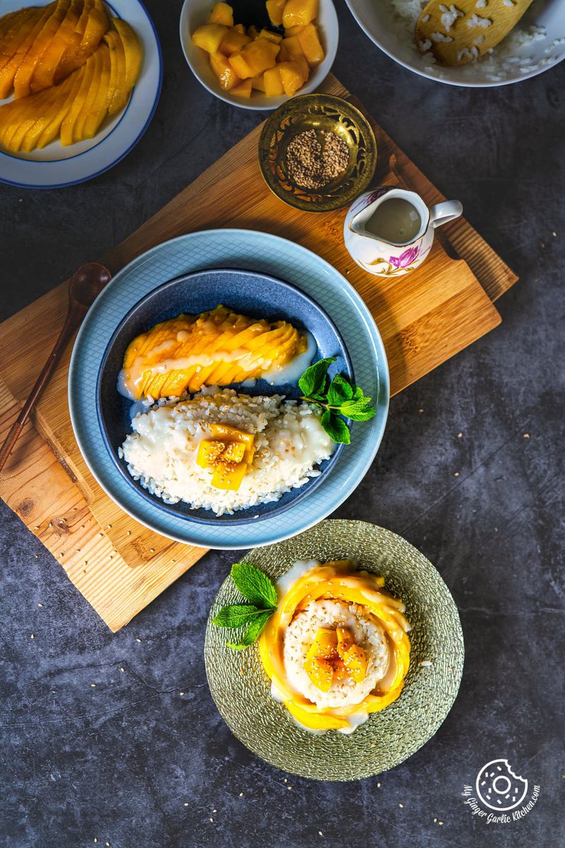 overhead shot of two thai mango sticky rice plates with mango slices and sesame seeds on the side