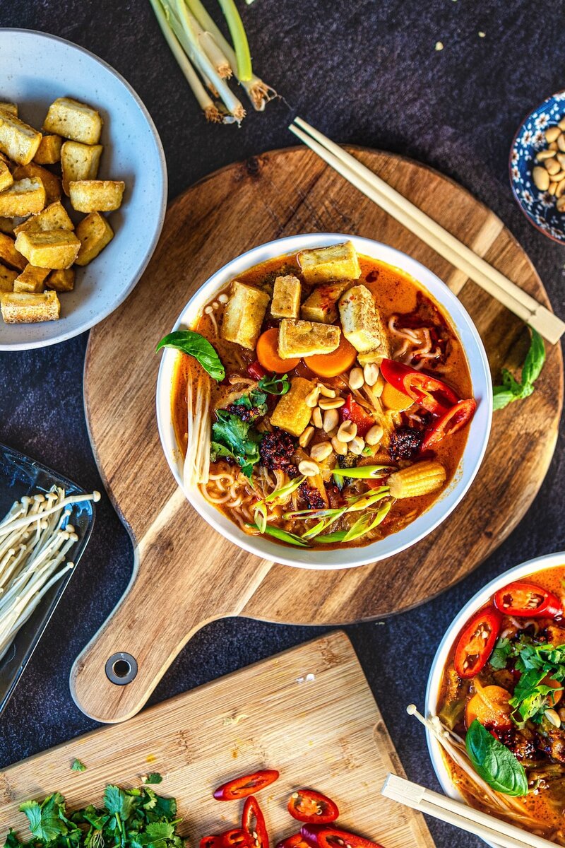 Thai red curry ramen with crispy tofu, vegetables, peanuts, and coconut curry broth served in a bowl