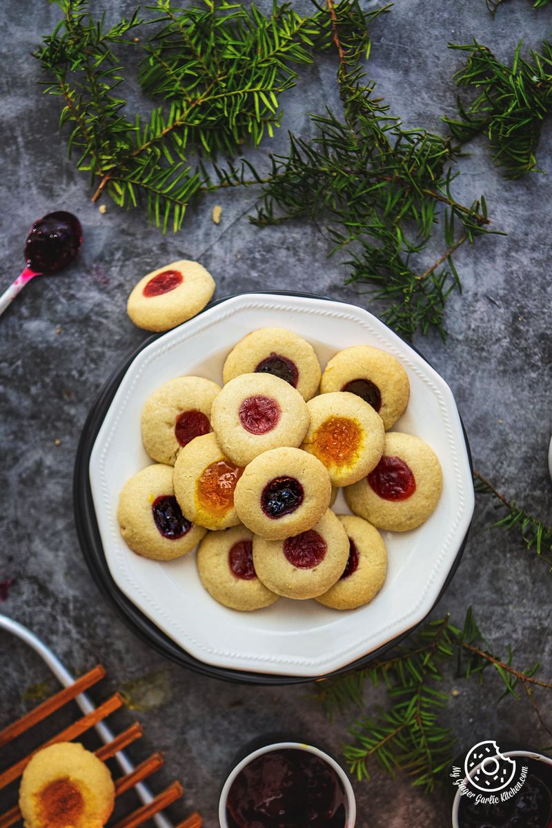 overhead shot of eggless thumbprint cookies arranged on a white plate with more cookies on the side