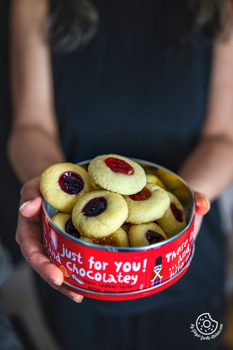closeup of a female holding red metal cookie box with thumbprint Cookies