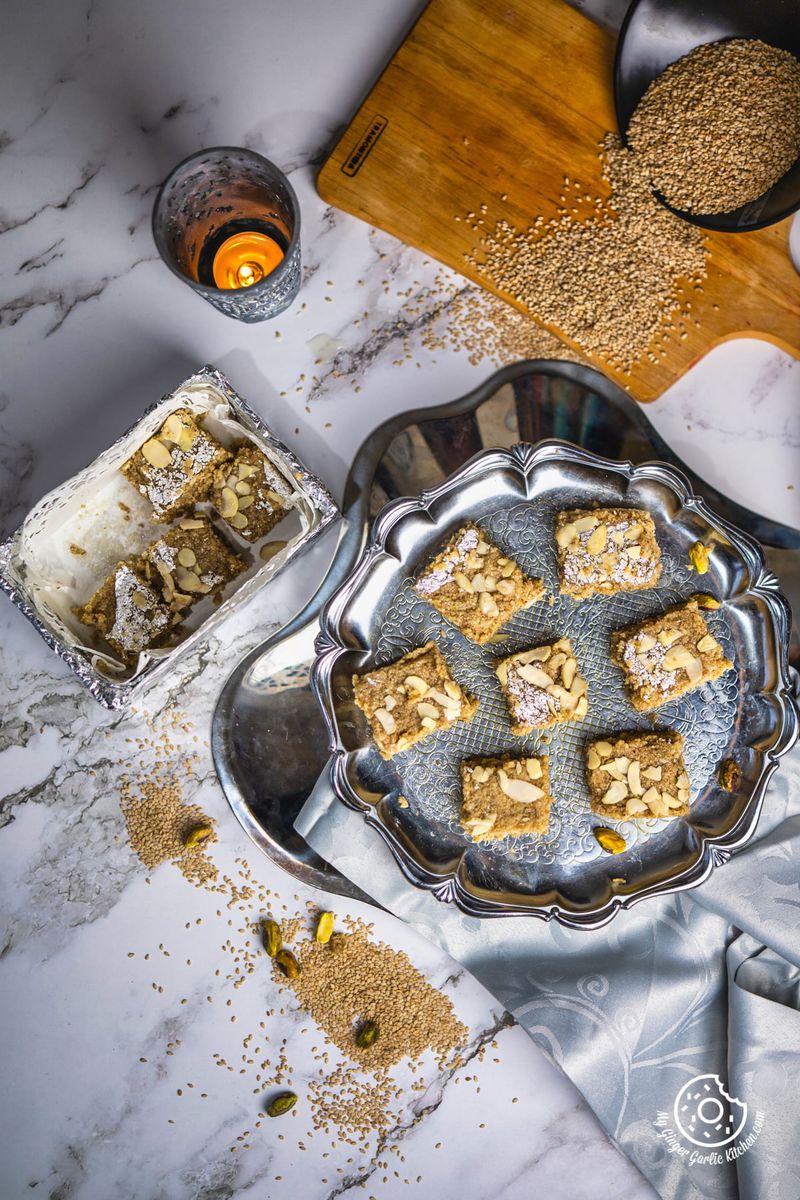 overhead shot of til burfi in served in a metal plate and in silver paper box