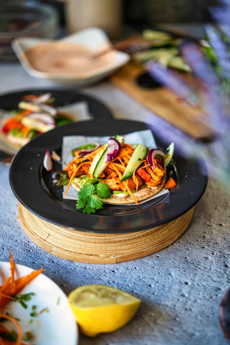 IA colorful plate of tofu bell pepper tacos garnished with cucumber slices and cilantro on a dark plate.