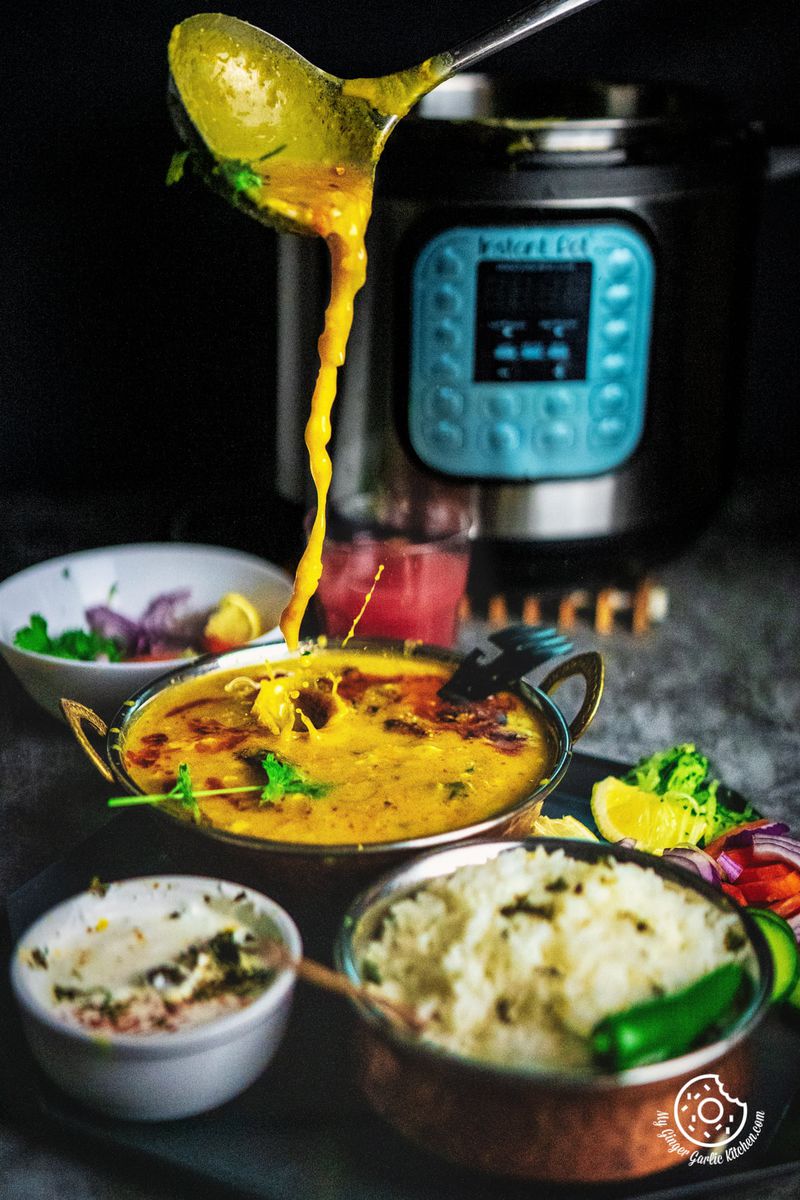 action shot of pouring Toor Dal Tadka from a ladle, capturing the steam and texture of the spiced lentil dish