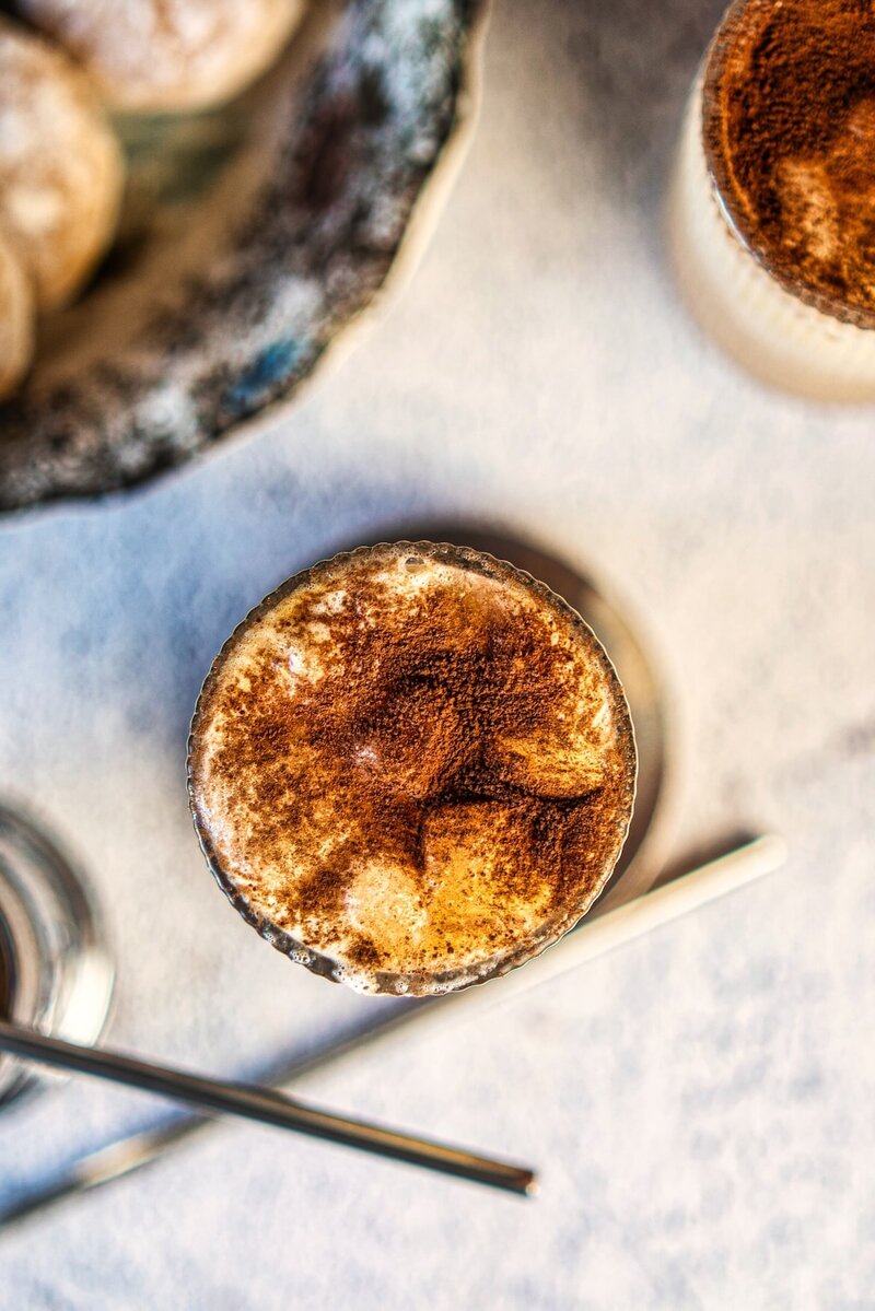 Top view of vanilla iced latte with thick foam and cocoa powder, smooth and creamy iced coffee texture