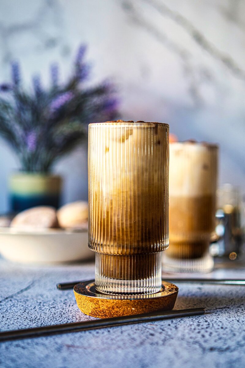 Layered vanilla iced latte with espresso and milk in a ribbed glass, easy homemade iced coffee recipe