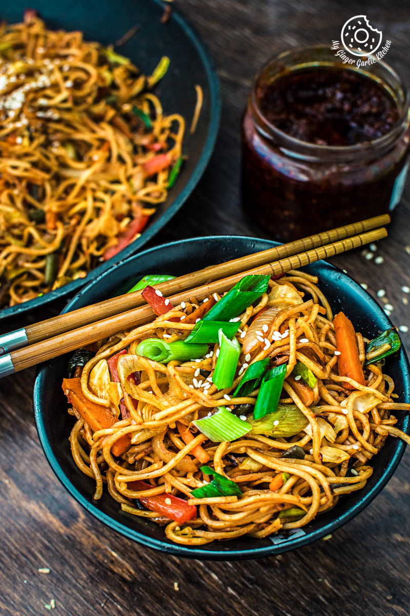 asian veg schezwan noodles with vegetables and sesame seeds in a bowl
