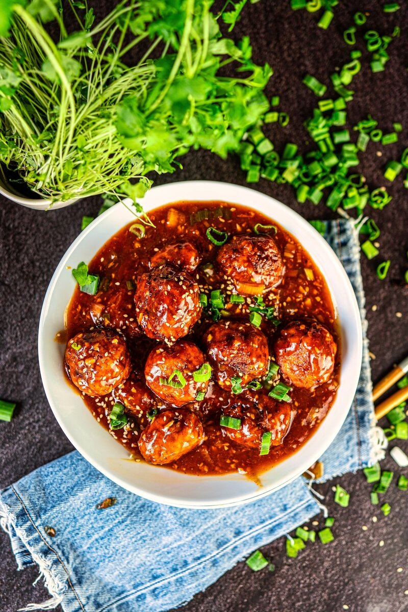 Top view of veg manchurian with crispy balls in rich Indo Chinese gravy, garnished with green onions and sesame seeds