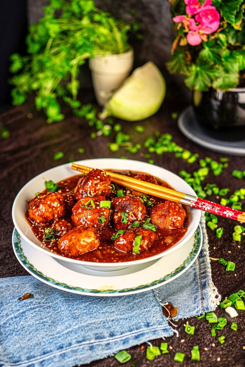 Restaurant style veg manchurian with crispy vegetable balls in thick spicy sauce, served in a bowl with chopsticks