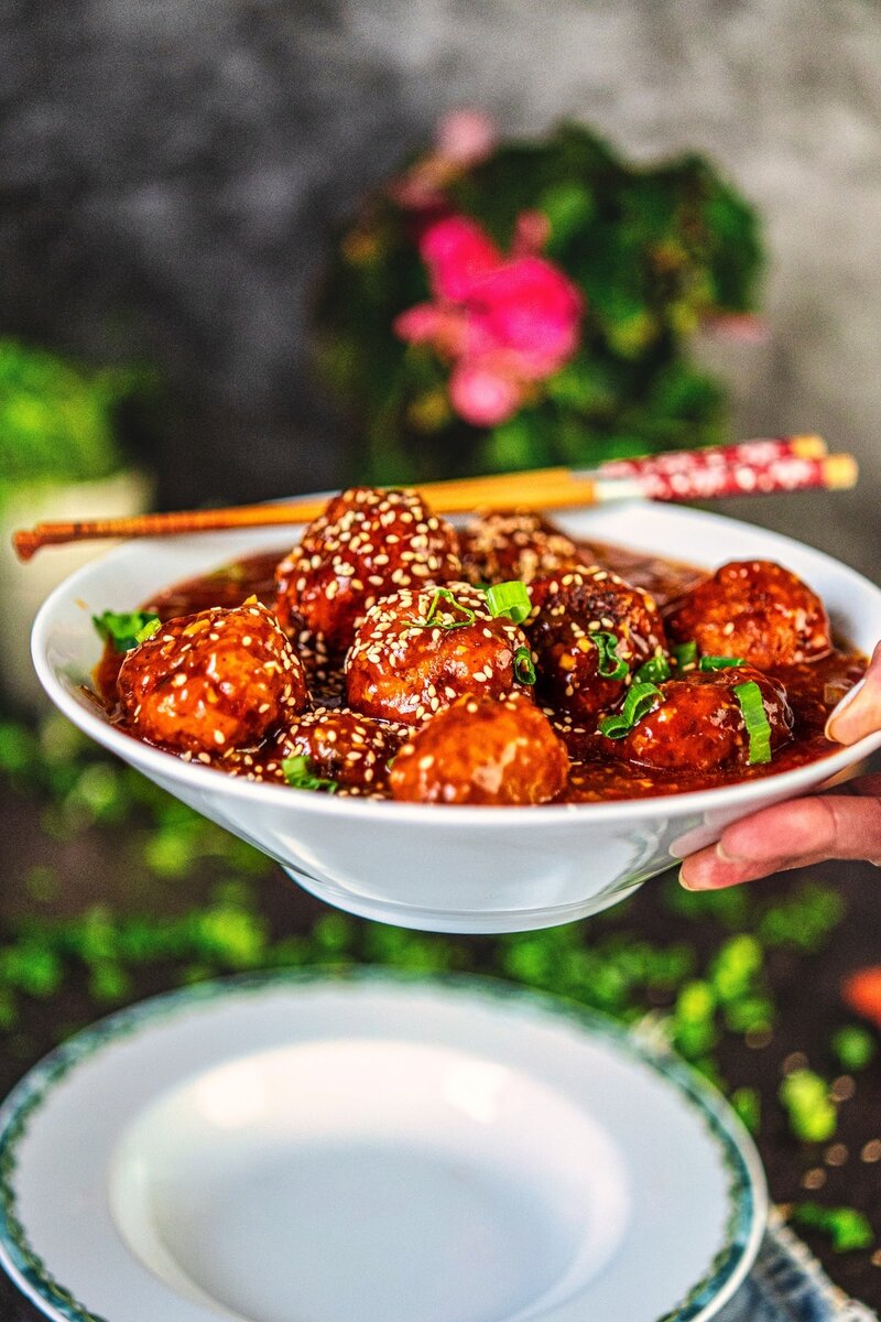 Homemade veg manchurian served in a bowl, crispy vegetable balls in spicy tangy gravy with sesame and spring onion garnish