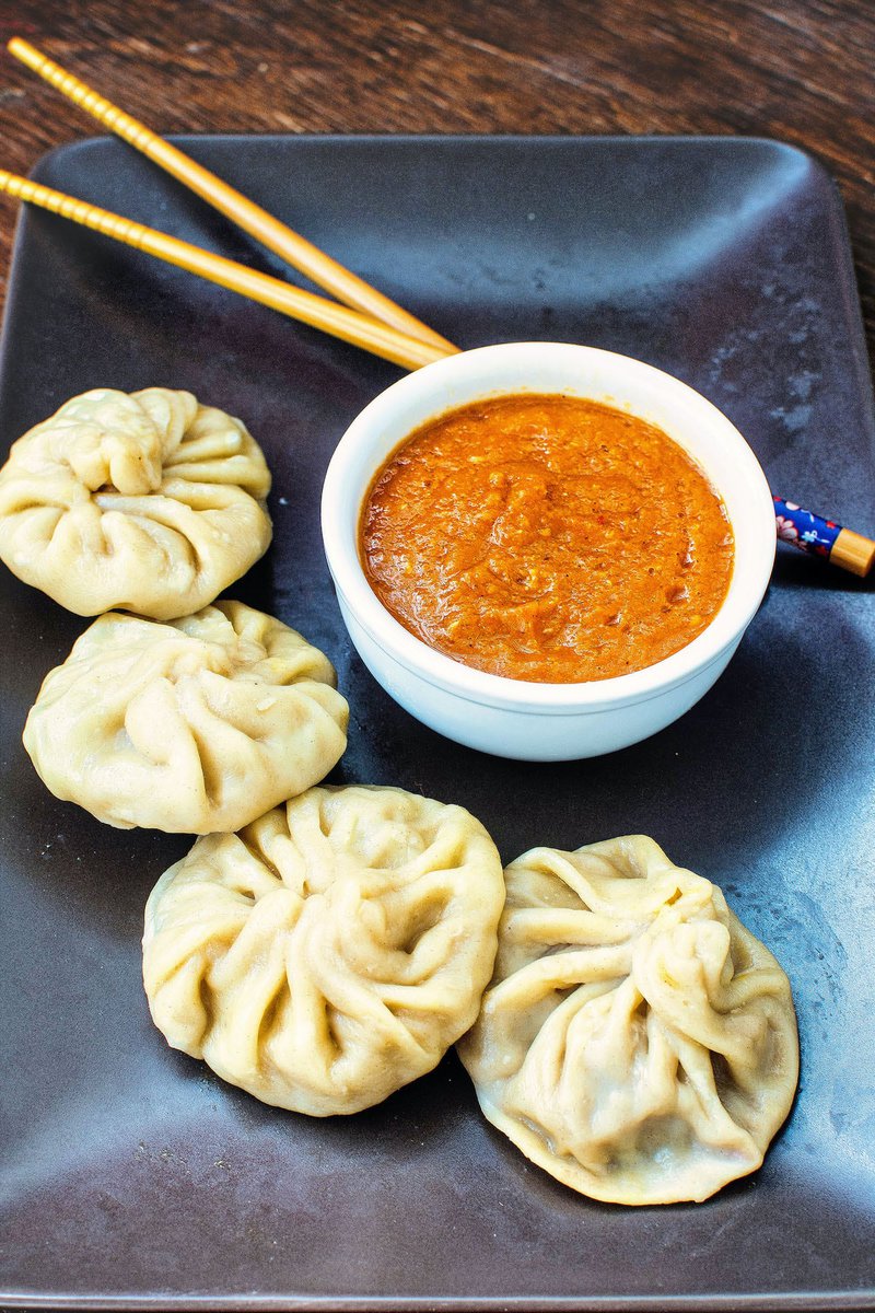 veg momos and spicy momos chutney  on a plate with chopsticks