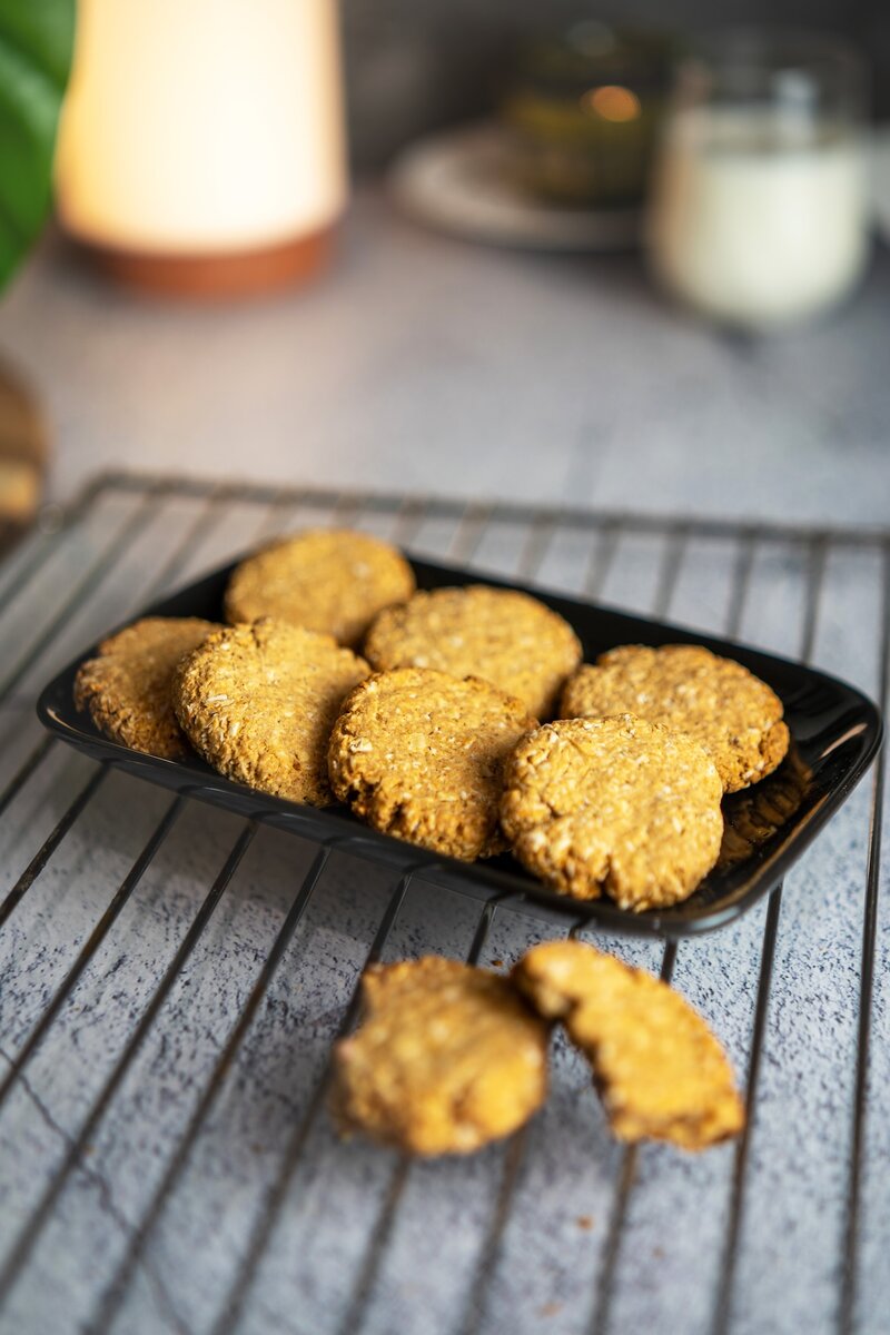 Top view of crisp and chewy vegan oatmeal cookies arranged on a black plate, healthy maple sweetened oatmeal cookies.