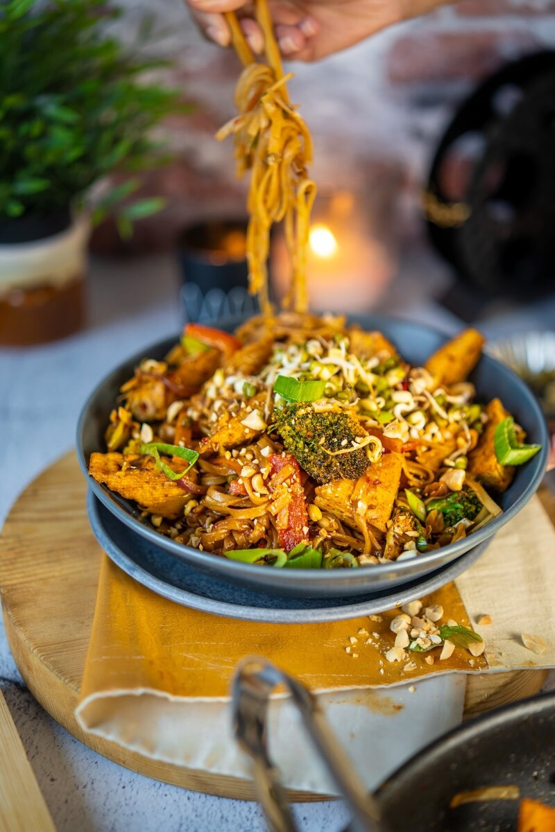 Homemade vegan Pad Thai noodles lifted with chopsticks, gluten free rice noodles tossed with tofu and tangy tamarind sauce.