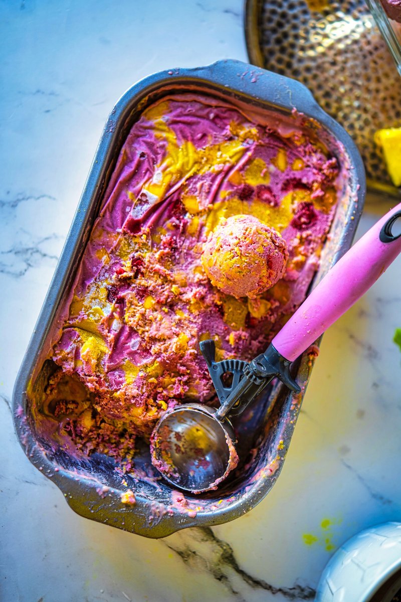 Vegan Strawberry Mango Ice Cream in a loaf pan with creamy pink and yellow swirls and an ice cream scoop