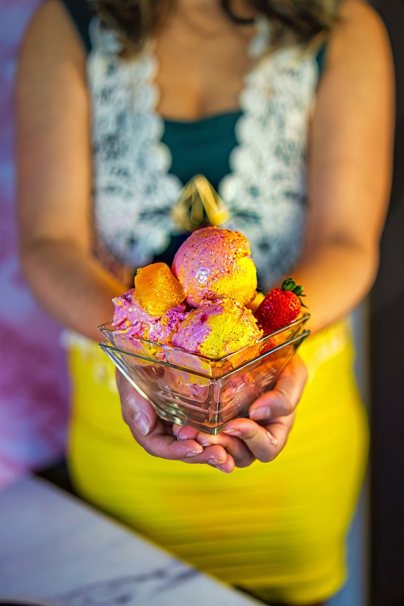 Bowl of homemade Vegan Strawberry Mango Ice Cream with fresh mango and strawberry garnish held for serving