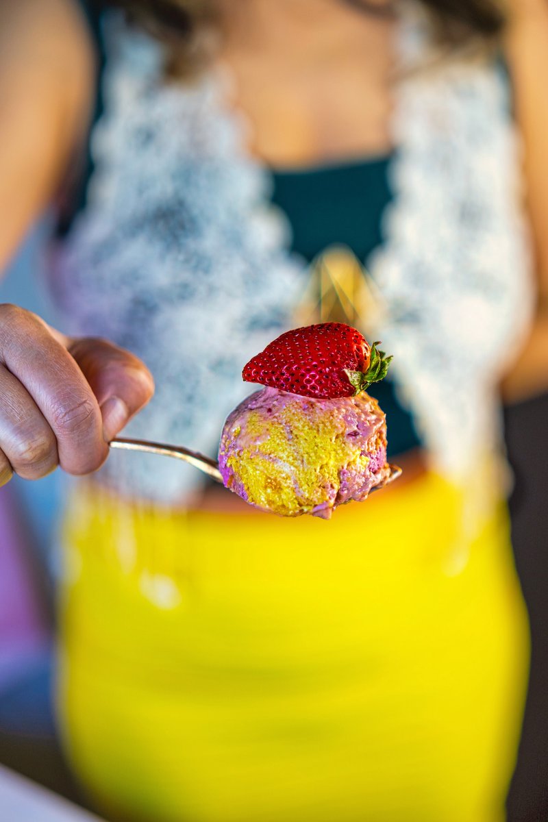Spoonful of creamy Vegan Strawberry Mango Ice Cream topped with a fresh strawberry, showing the dual-colored swirls