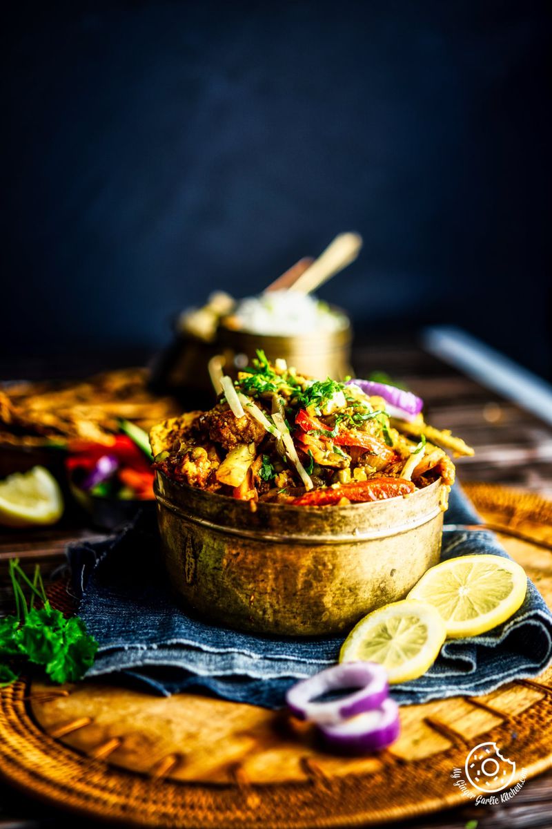 vegetable jalfrezi served in a brass bowl kept on a wooden board