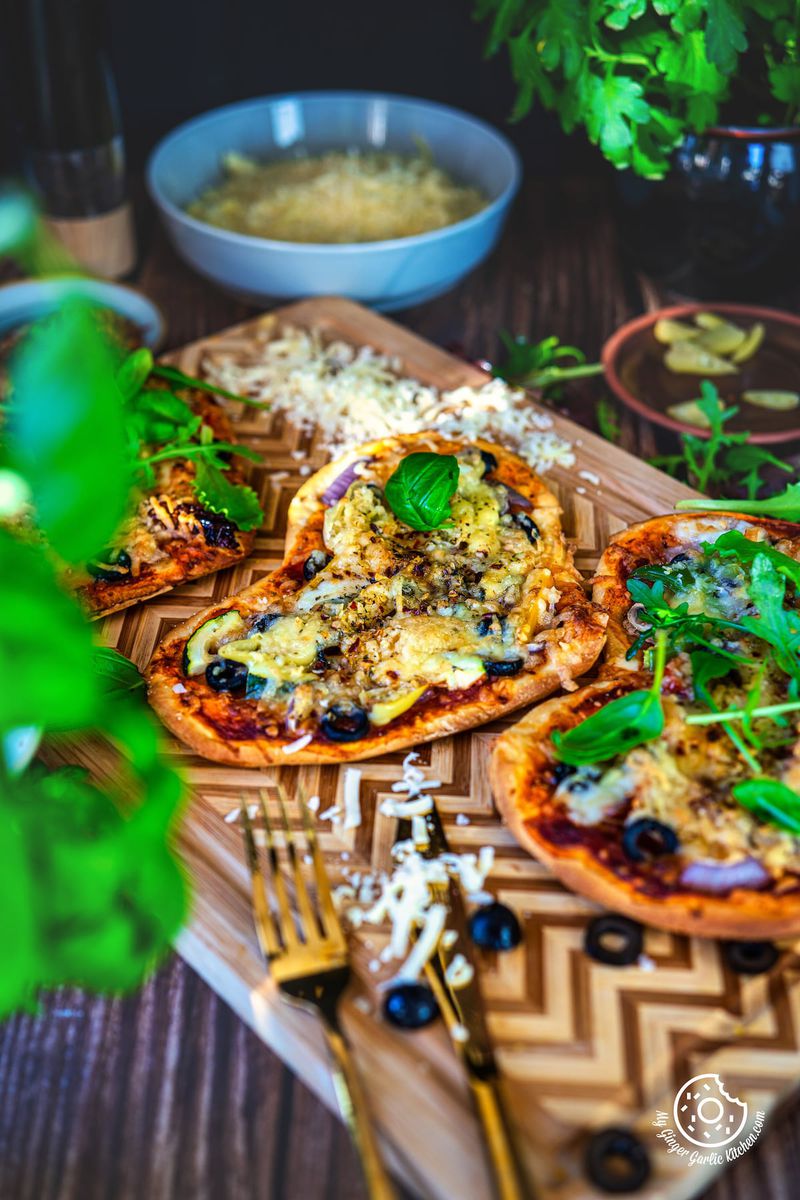 3 vegetarian heart pizza sitting on top of a wooden cutting board