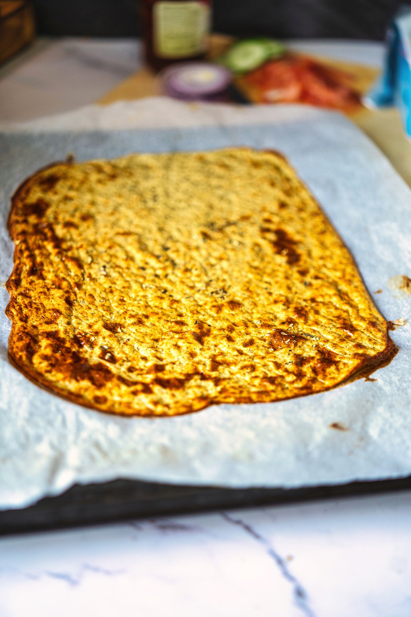 Freshly baked viral cottage cheese flatbread cooling on a parchment-lined baking tray, showcasing its golden brown crust.