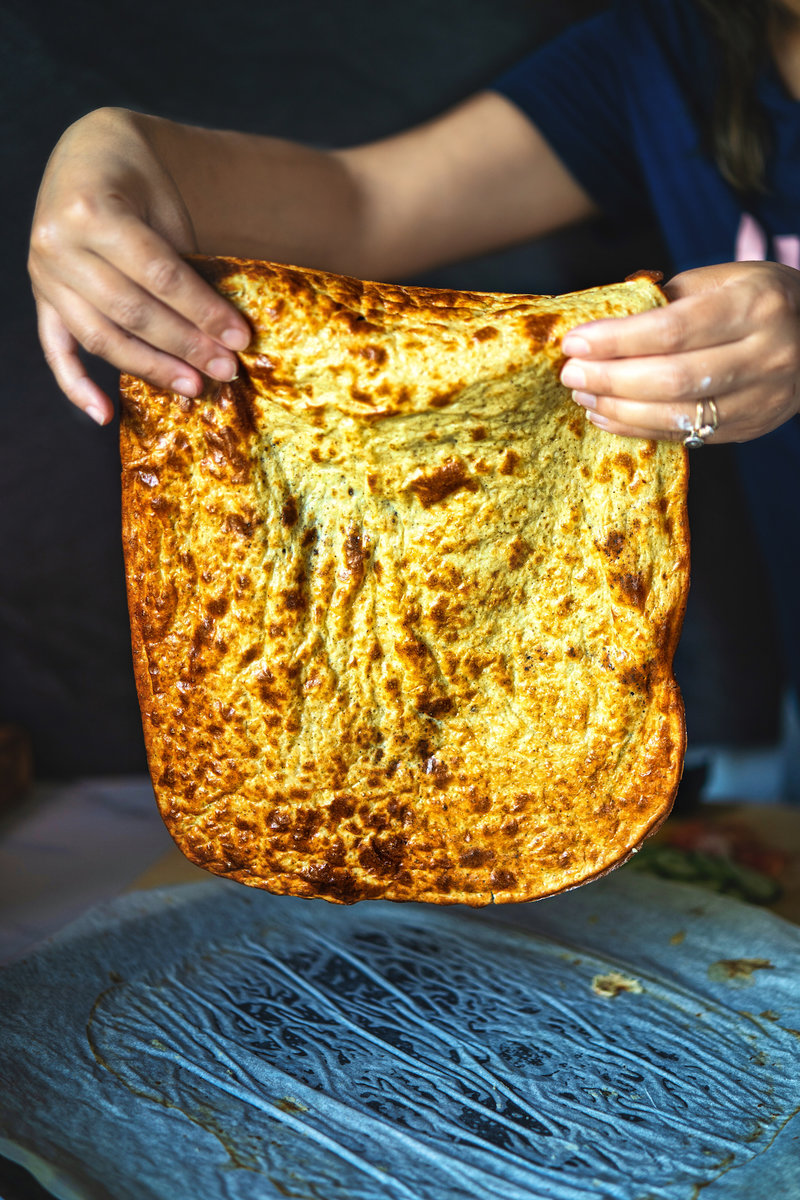 A close-up of the golden brown viral cottage cheese flatbread being held up, highlighting its crispy and airy texture.