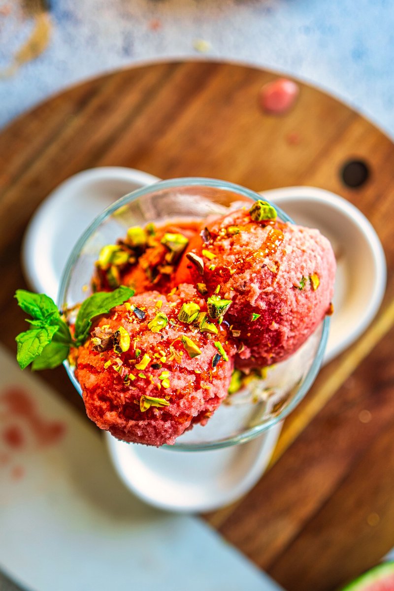 Viral Watermelon Ice Cream scoops topped with chopped pistachios and maple syrup, photographed from above in a glass dessert bowl