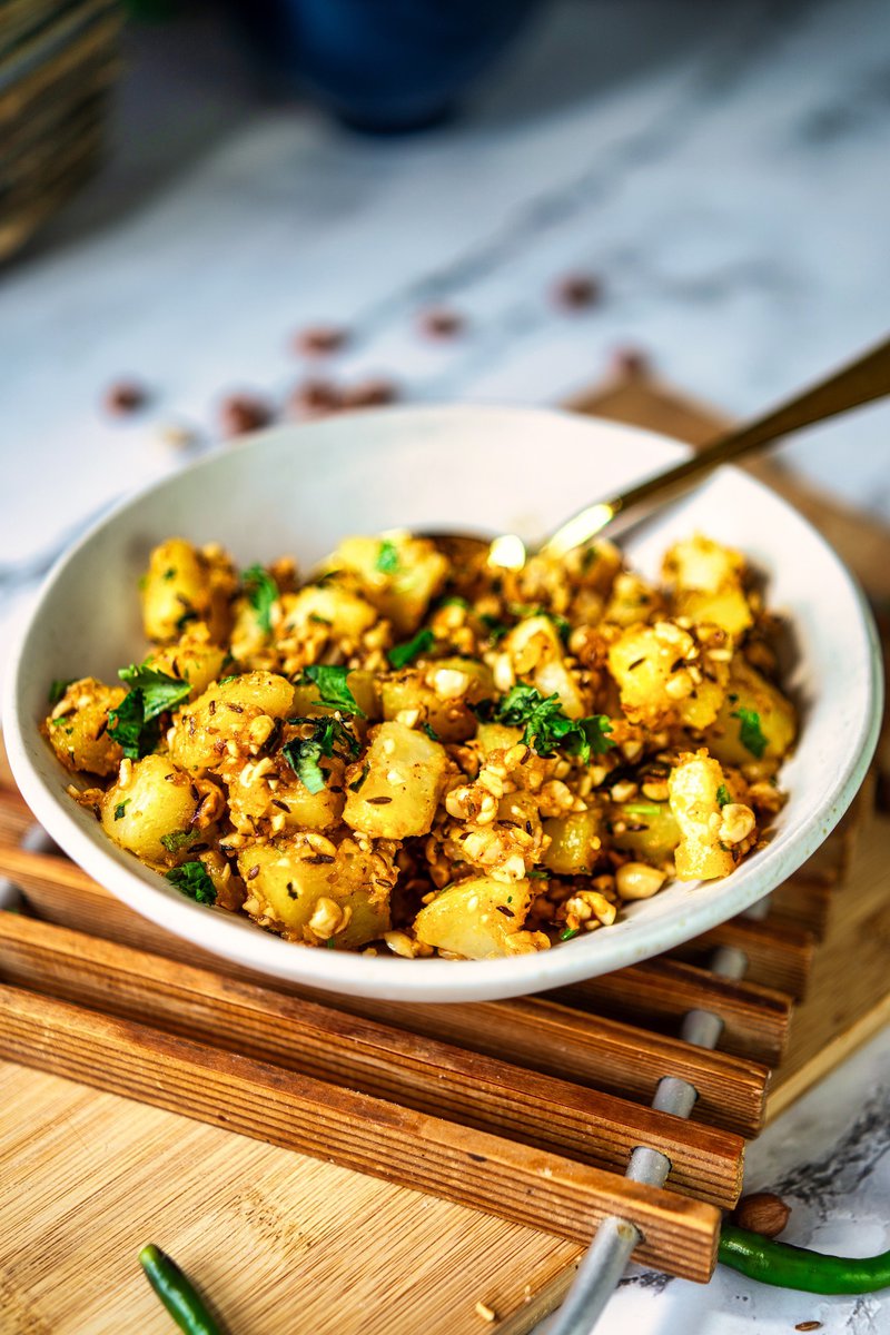 A bowl of vrat wale aloo garnished with fresh herbs and peanuts.