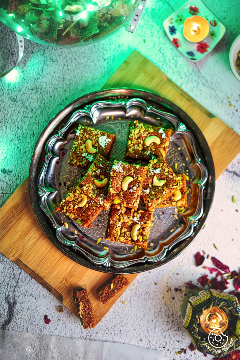 top view of a plate of walnut burfi or akhrot burfi garnished with cashews and walnuts on a table with a candle
