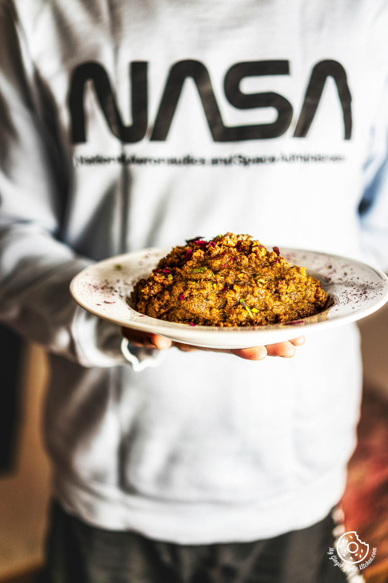 a plate of Akhrot Halwa being held by a man in a nasa sweatshirt