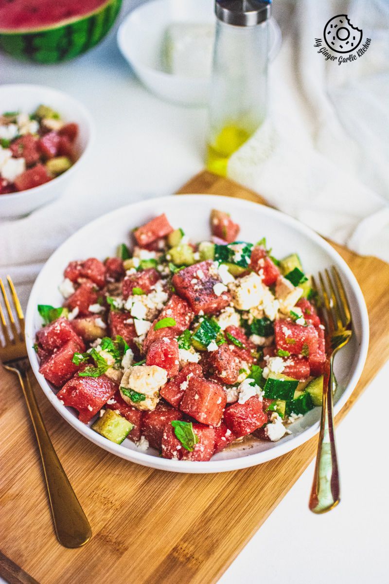 Watermelon Cucumber Feta Salad on white plate with golden serving spoons