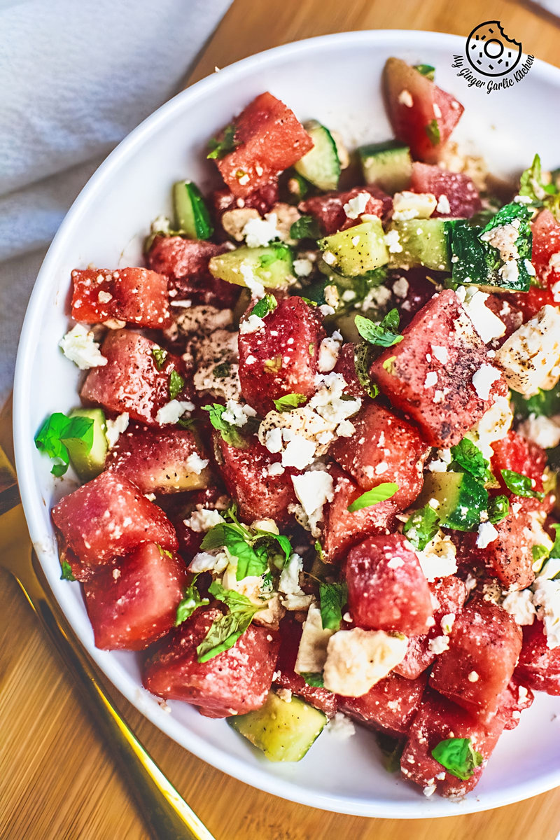 Watermelon Cucumber Feta Salad on white plate with golden serving spoons