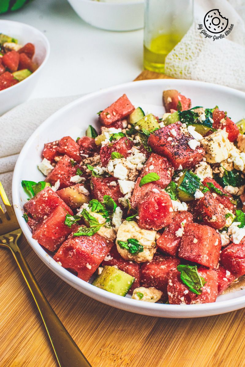 Watermelon Cucumber Feta Salad on white plate with golden serving spoons