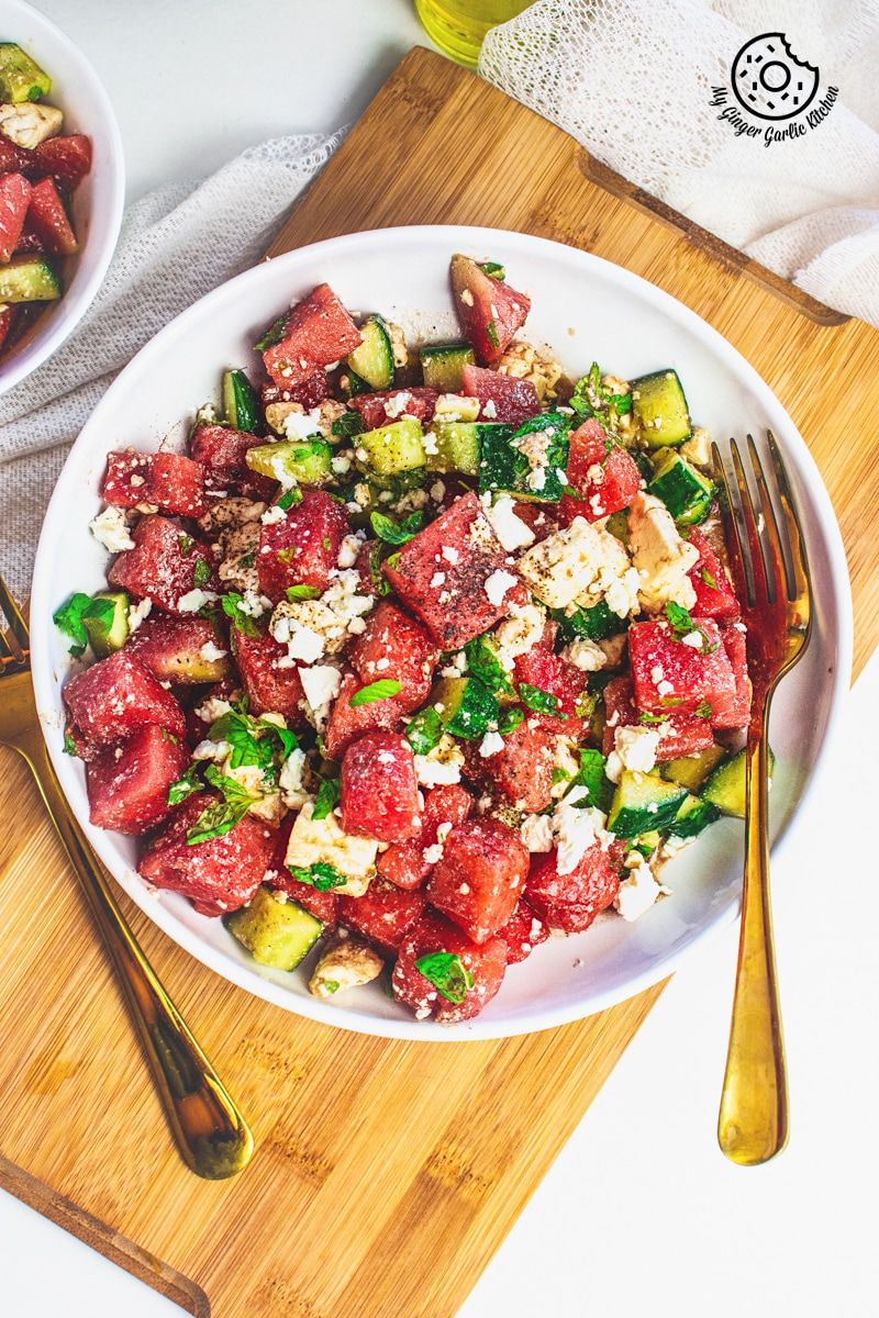 Watermelon Cucumber Feta Salad on white plate with golden serving spoons