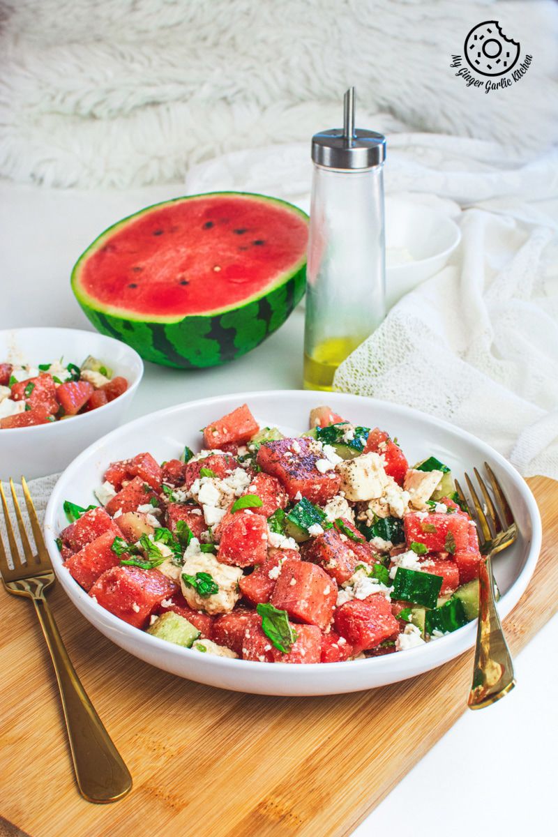 Watermelon Cucumber Feta Salad on white plate with golden serving spoons