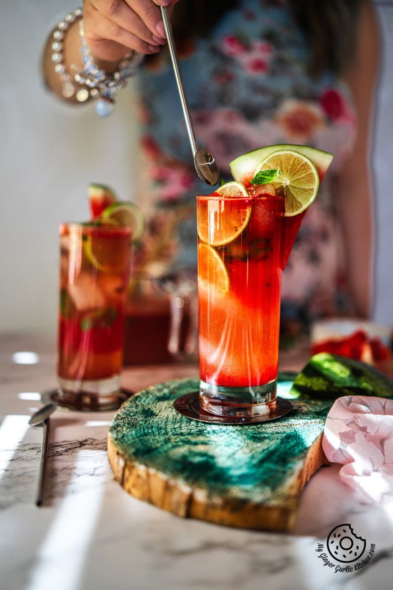 a female holding a steel straw over the watermelon mojito glass