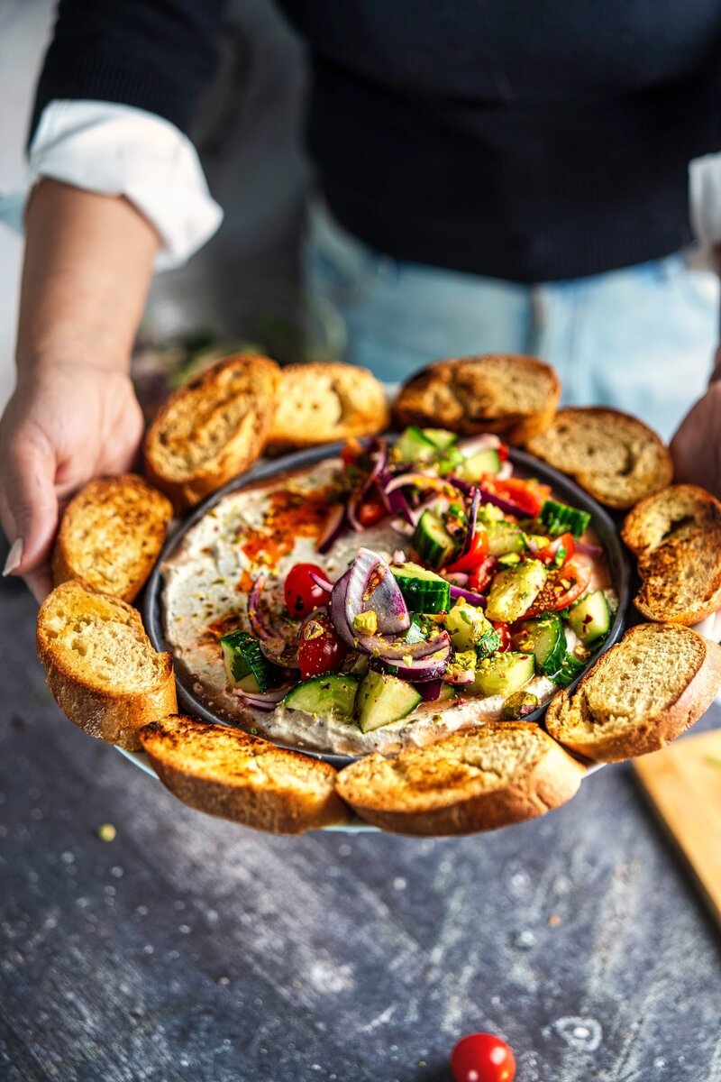 Mediterranean cottage cheese dip served on a plate with golden toasted baguette slices