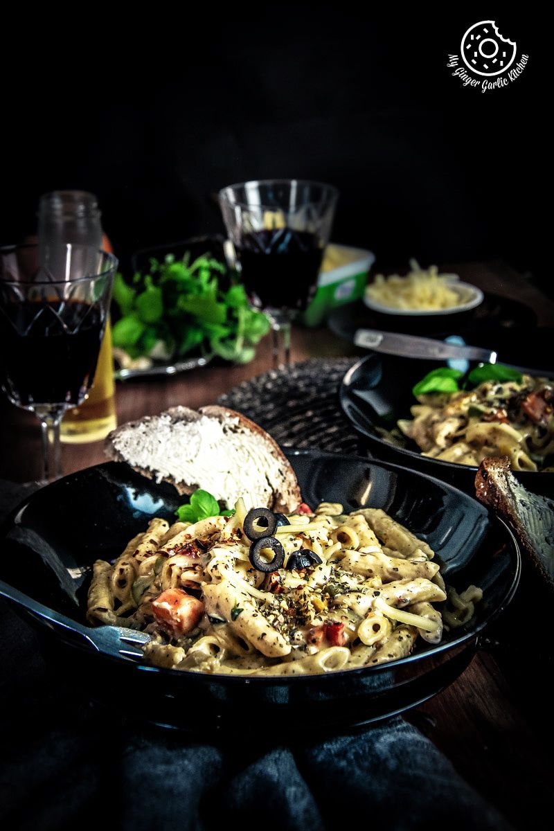 two plates of white sauce pasta with bread on the table