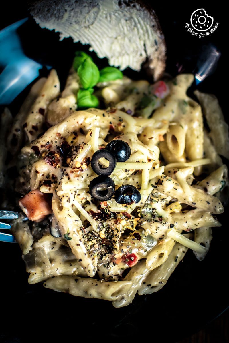 white sauce pasta with black olives and herbs on a plate