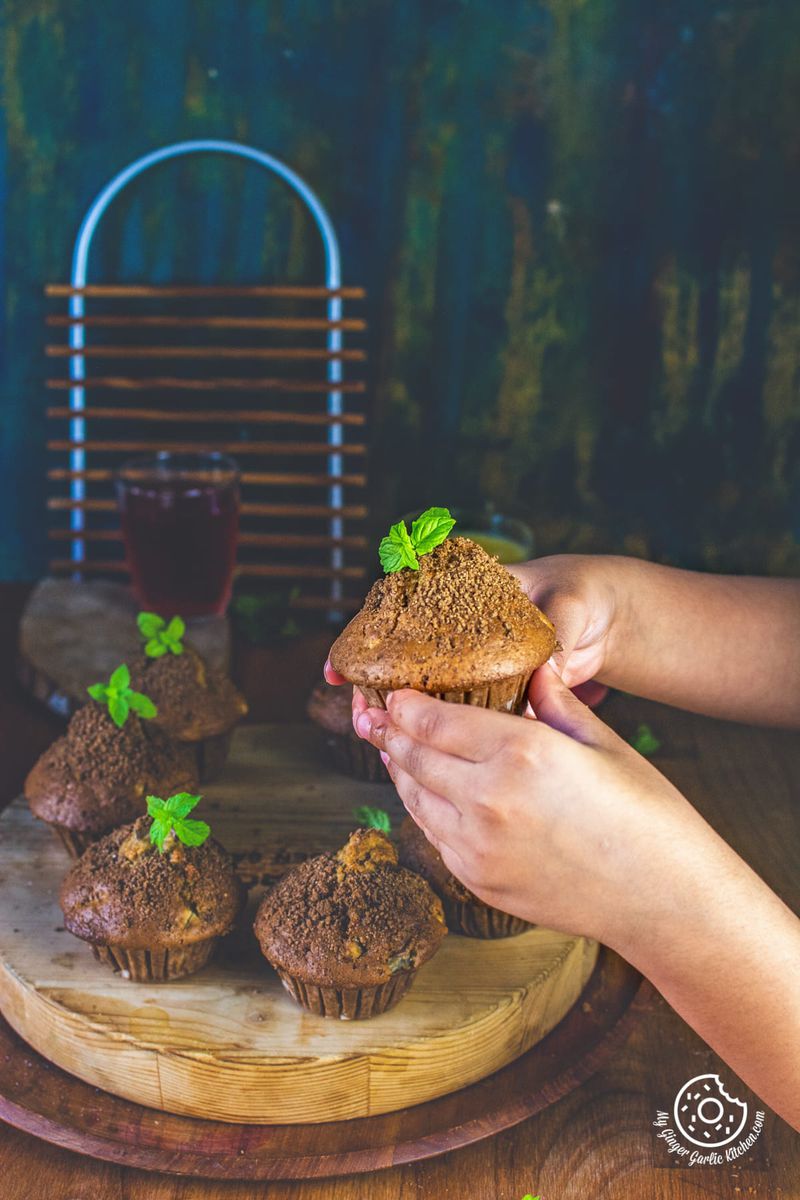 a kid holding whole wheat peach muffin topped with mint leaves