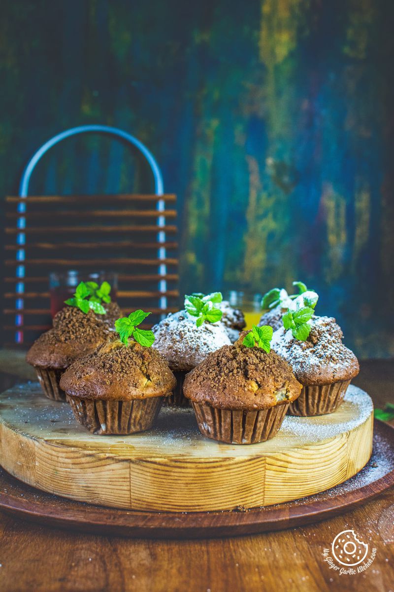 whole wheat peach muffins topped with mint leaves served on a wooden board