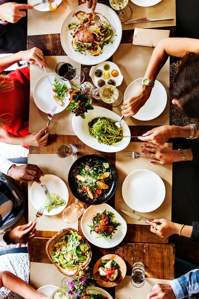 Overhead view of a group of people dining together with various dishes and beverages on a table.