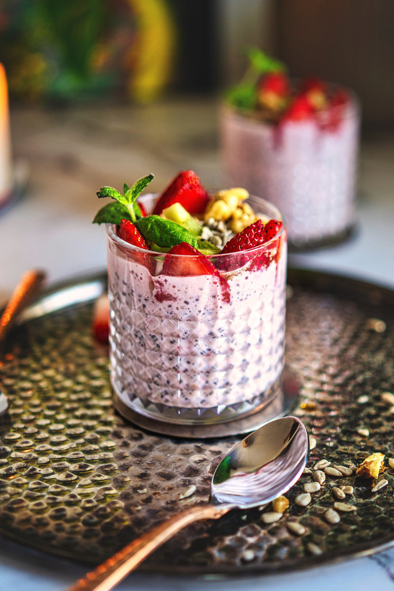 Elegant Greek yogurt chia pudding garnished with strawberries and nuts on a decorative plate.