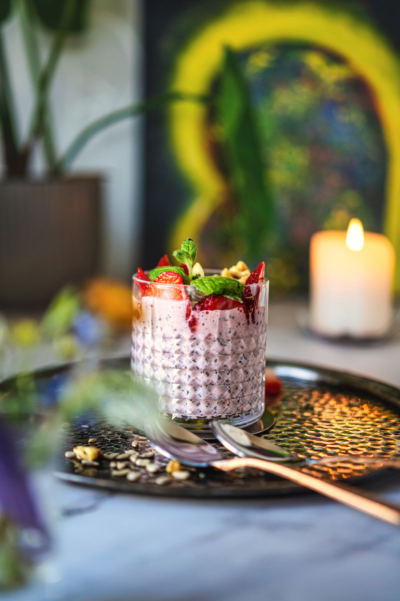 Artistic close-up of strawberry chia pudding in a glass, garnished with fresh mint.